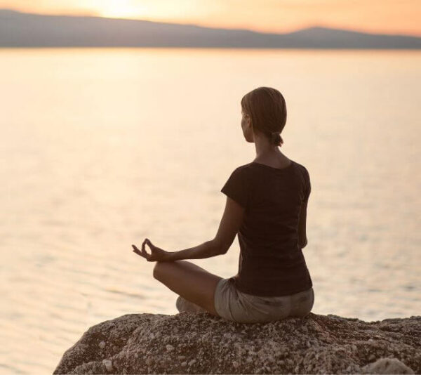 Meditation, Frau im Sonnenaufgang in meditativer Haltung