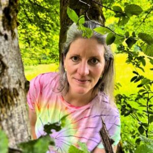 Sabine_Martini_Blätter_direkt_bunt Sabine Martini zwischen Blättern und Baum, gelber Hintergrund Natur